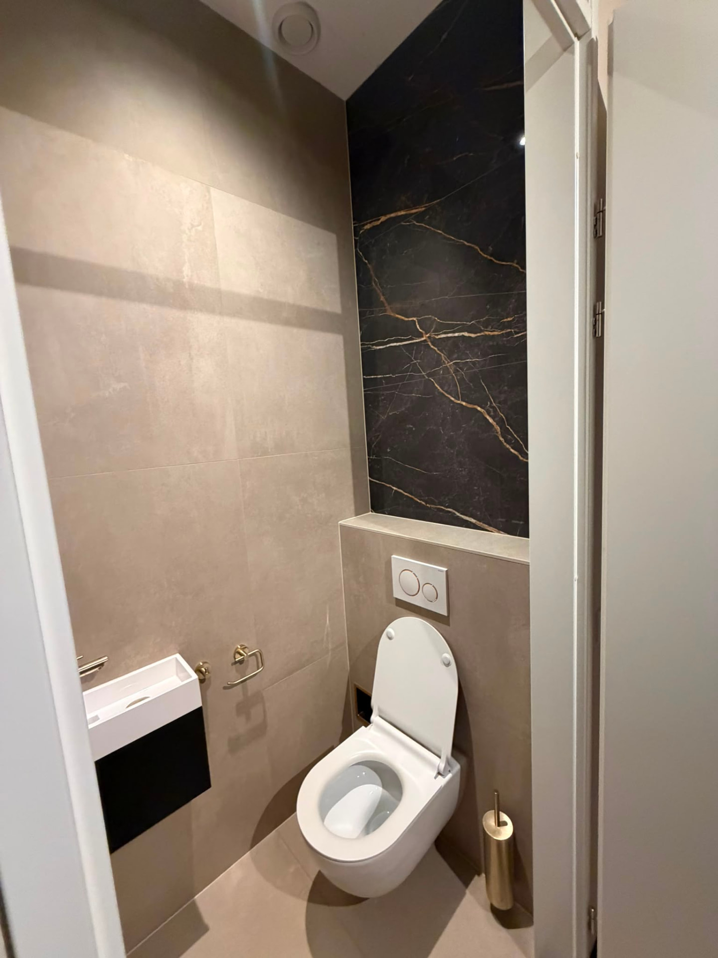 Toilet met zandkleurige tegels en donkere accentwand